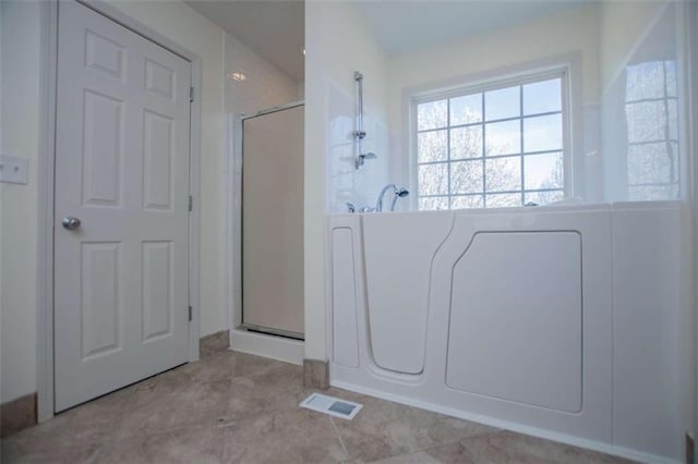 bathroom with tile patterned flooring, visible vents, and a shower with shower door