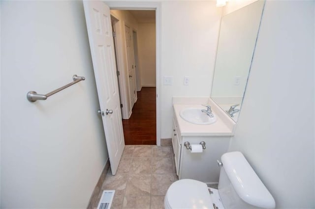 half bath with vanity, toilet, and visible vents