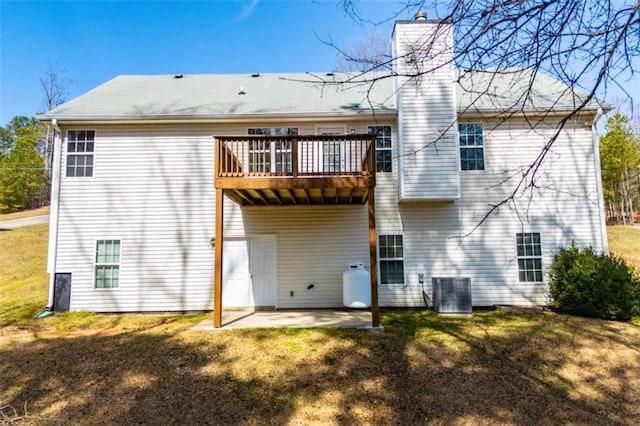 back of house featuring a yard, a patio area, central AC, and a chimney