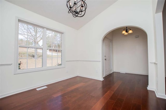 empty room with wood finished floors, visible vents, lofted ceiling, arched walkways, and a chandelier