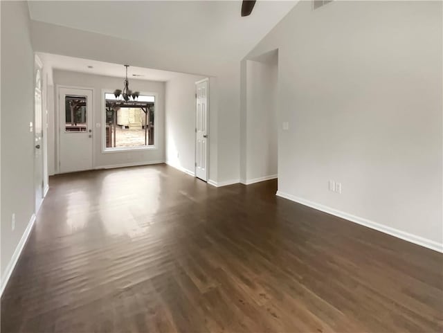 unfurnished living room with a notable chandelier, vaulted ceiling, and dark hardwood / wood-style flooring