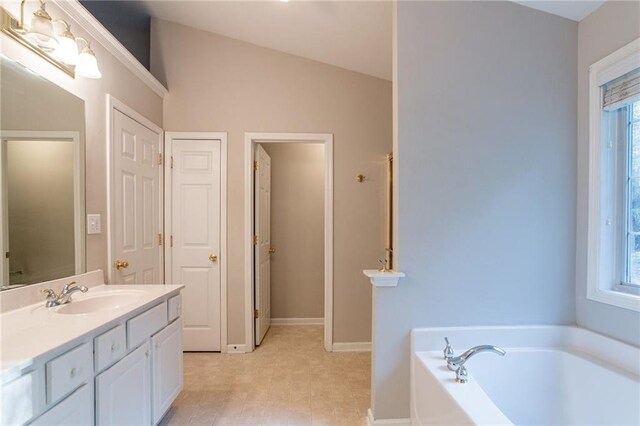 bathroom featuring vanity, a bath, and vaulted ceiling