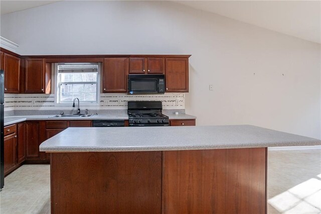 kitchen with sink, vaulted ceiling, a kitchen island, and black appliances