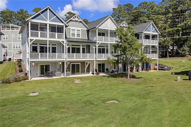 rear view of property with a lawn, a balcony, and a patio area