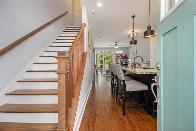 staircase with wood-type flooring and ceiling fan