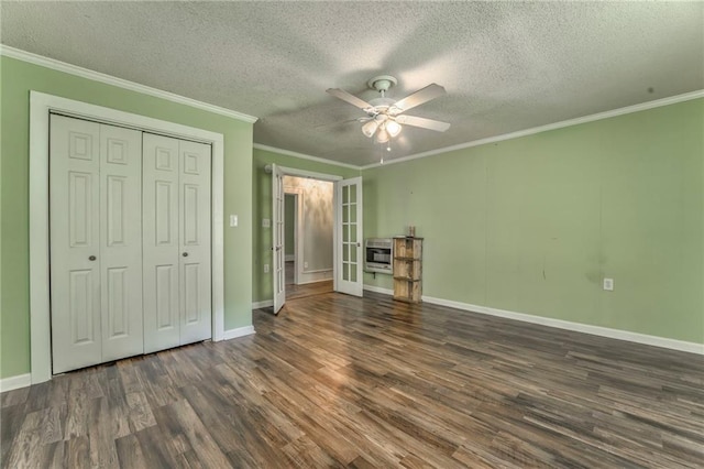 unfurnished bedroom with heating unit, wood finished floors, ornamental molding, baseboards, and a closet
