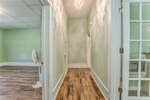 corridor featuring wood finished floors, baseboards, and a chandelier