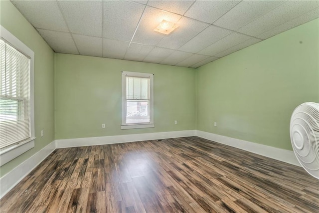 unfurnished room with dark wood finished floors, baseboards, and a paneled ceiling
