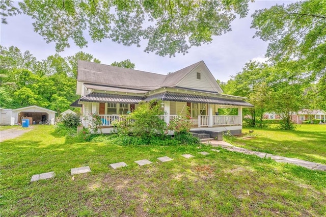 view of front of home with a porch, a detached carport, a front yard, and a shingled roof