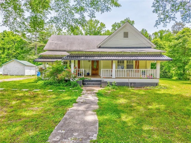 farmhouse featuring covered porch, a front lawn, and roof with shingles