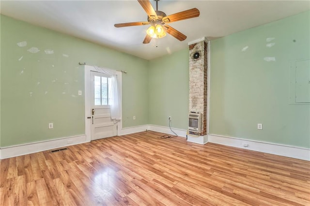unfurnished room featuring wood finished floors, heating unit, a ceiling fan, and baseboards