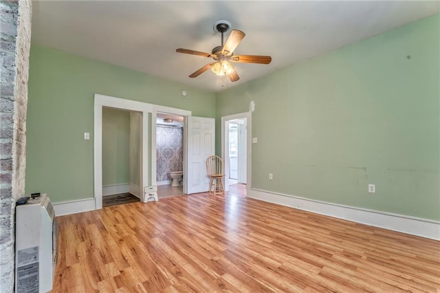 unfurnished bedroom featuring light wood-style floors, baseboards, a ceiling fan, and ensuite bath