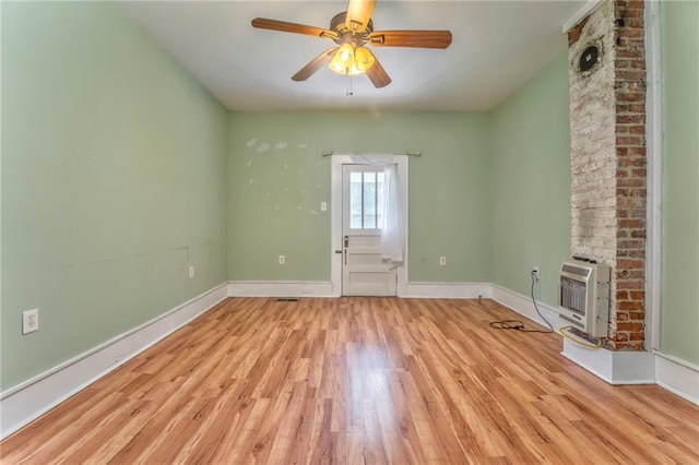 unfurnished living room with heating unit, wood finished floors, a ceiling fan, and baseboards