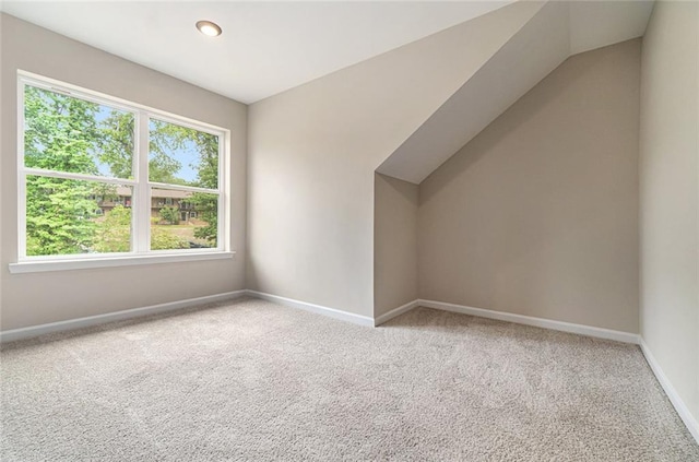 additional living space featuring vaulted ceiling and light carpet