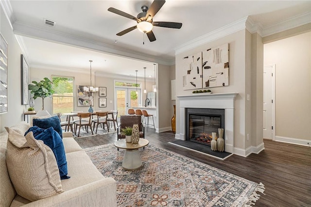 living room with ornamental molding, dark hardwood / wood-style flooring, and ceiling fan with notable chandelier