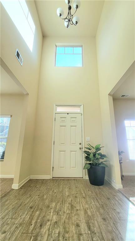 foyer featuring hardwood / wood-style flooring, a towering ceiling, and a chandelier