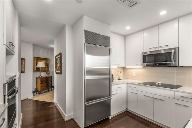 kitchen with backsplash, visible vents, dark wood-style floors, stainless steel appliances, and white cabinetry