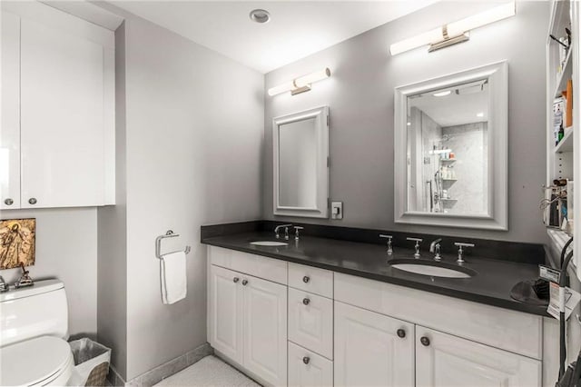 bathroom featuring double vanity, a sink, baseboards, and toilet
