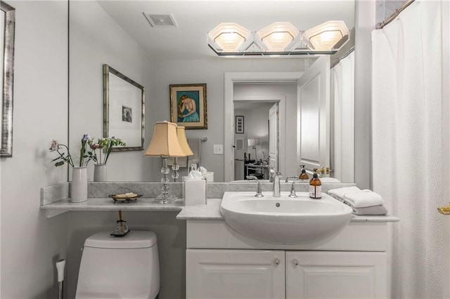 full bathroom with vanity, toilet, and visible vents