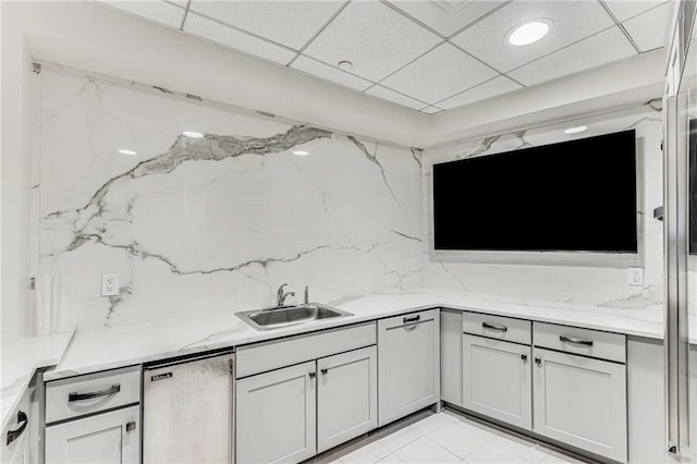 kitchen with fridge, light stone countertops, a sink, and tasteful backsplash