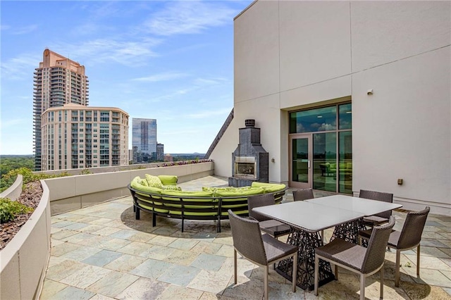 view of patio with a city view, outdoor dining space, and an outdoor living space with a fireplace