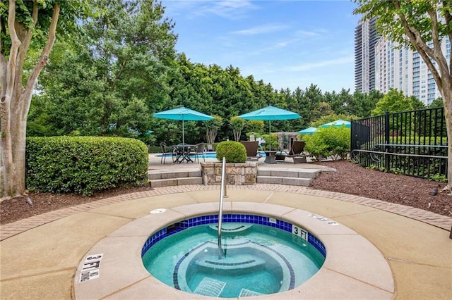 community pool with a patio, a hot tub, and fence