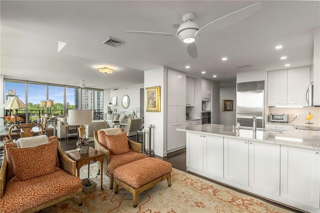 kitchen with visible vents, a peninsula, open floor plan, ceiling fan, and stainless steel built in refrigerator