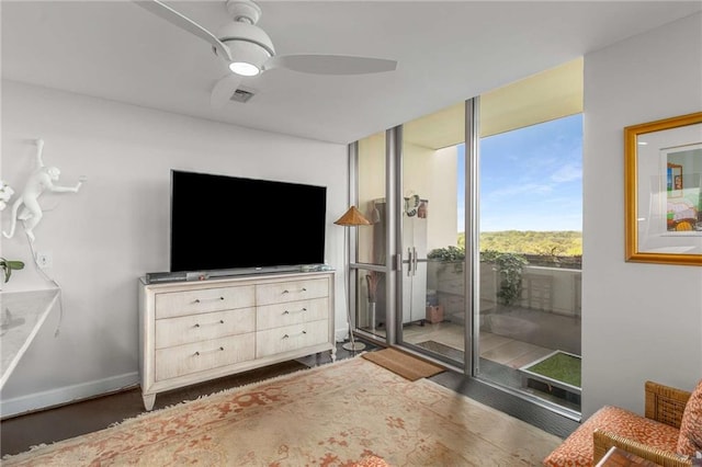 interior space featuring visible vents, wood finished floors, baseboards, access to outside, and a ceiling fan