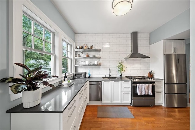 kitchen featuring a sink, backsplash, dark countertops, appliances with stainless steel finishes, and wall chimney exhaust hood