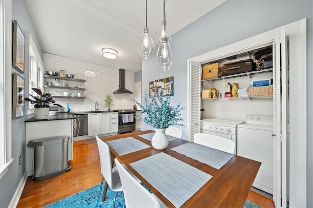 dining space with light wood finished floors and separate washer and dryer