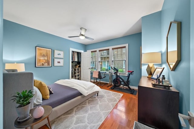 bedroom featuring a closet, a ceiling fan, baseboards, and wood finished floors