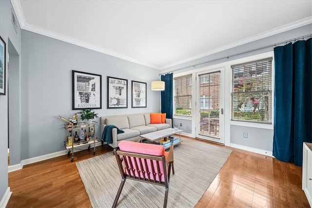 living room featuring wood finished floors, baseboards, and ornamental molding