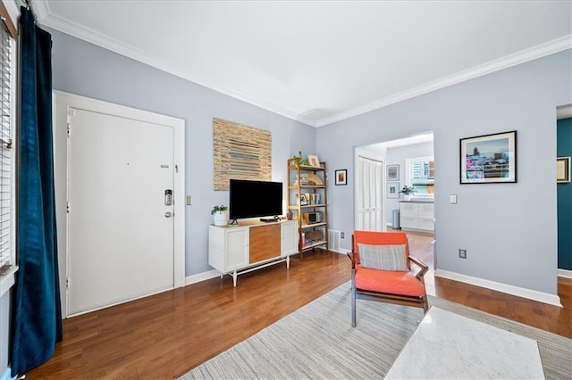 sitting room featuring baseboards, wood finished floors, and ornamental molding