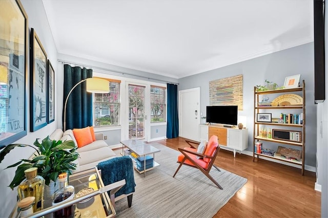 living area featuring crown molding, wood finished floors, and baseboards