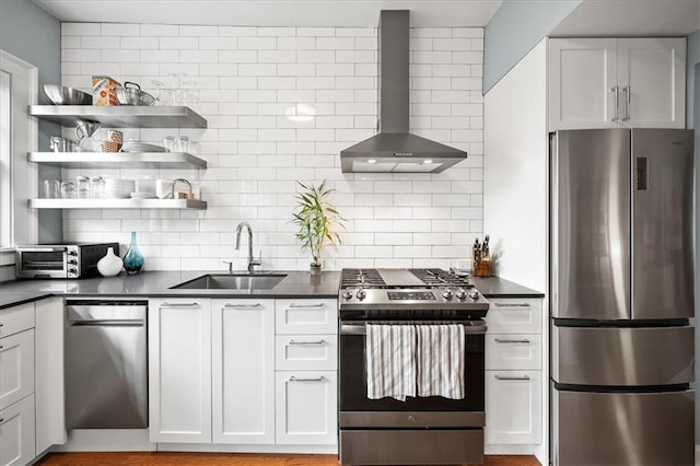 kitchen featuring a sink, dark countertops, appliances with stainless steel finishes, and wall chimney range hood