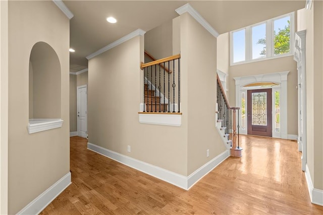 foyer entrance with light hardwood / wood-style flooring and ornamental molding