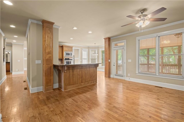 kitchen featuring kitchen peninsula, ceiling fan, stainless steel appliances, hanging light fixtures, and crown molding