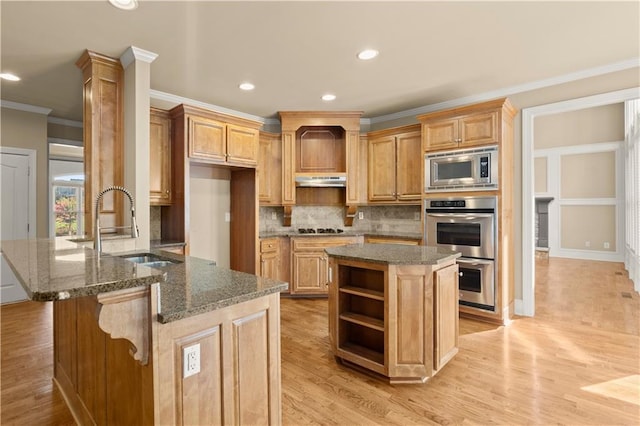 kitchen with dark stone countertops, a center island, kitchen peninsula, sink, and stainless steel appliances