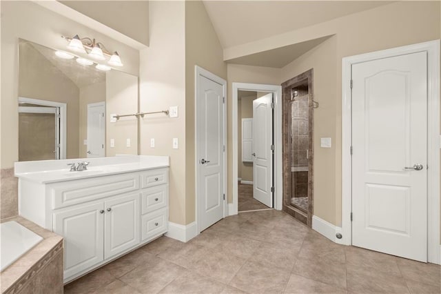 bathroom featuring tile patterned flooring, vanity, a tile shower, and vaulted ceiling