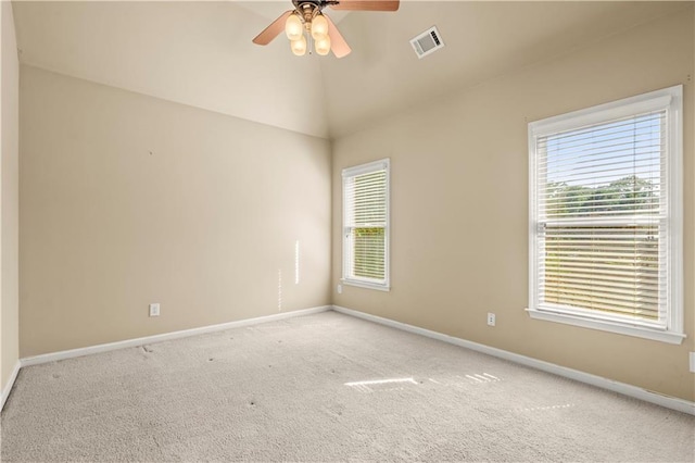 carpeted empty room with ceiling fan, plenty of natural light, and vaulted ceiling