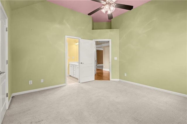 unfurnished bedroom featuring ceiling fan, light colored carpet, and ensuite bath