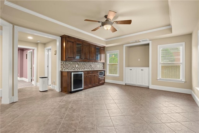 kitchen featuring a wealth of natural light, a raised ceiling, wine cooler, and backsplash