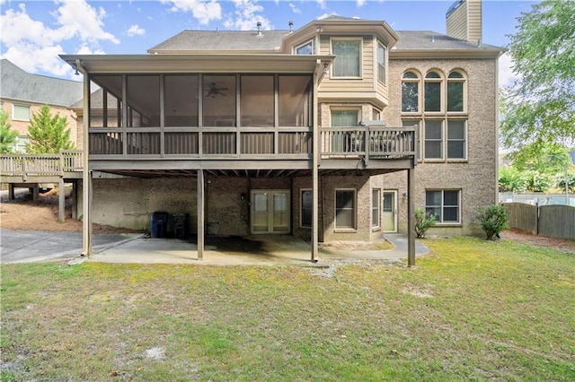 rear view of house with a wooden deck, a patio area, a yard, and a sunroom