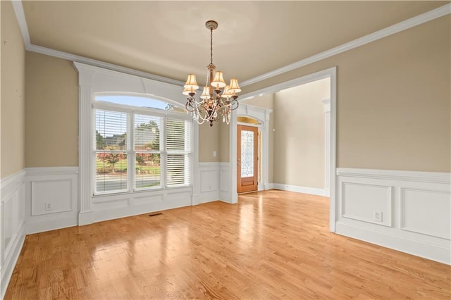 unfurnished dining area featuring ornamental molding, light hardwood / wood-style flooring, and a notable chandelier