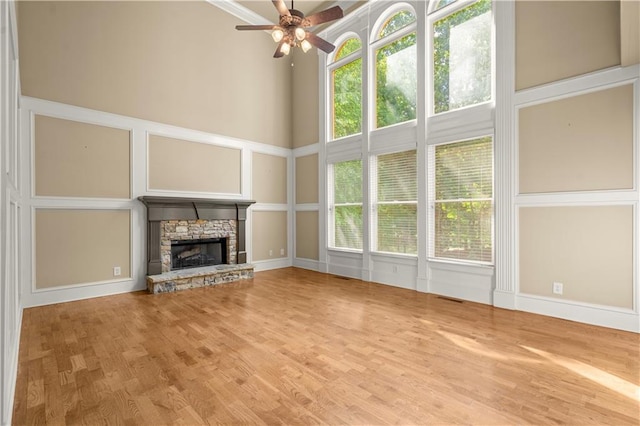 unfurnished living room featuring ceiling fan, hardwood / wood-style flooring, and a stone fireplace