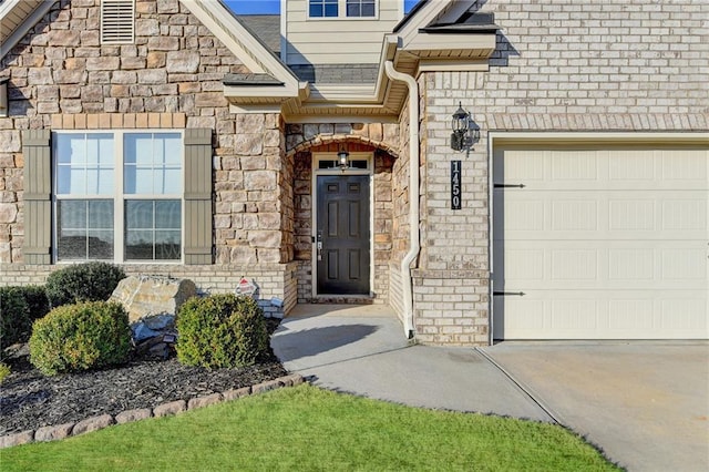 view of exterior entry with stone siding, an attached garage, and concrete driveway