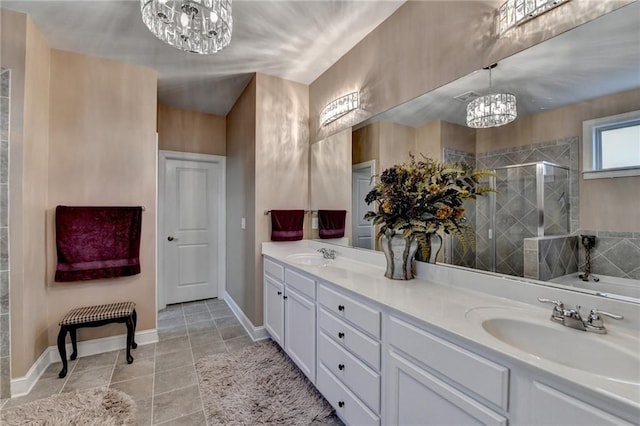 bathroom with double vanity, a shower stall, an inviting chandelier, and a sink