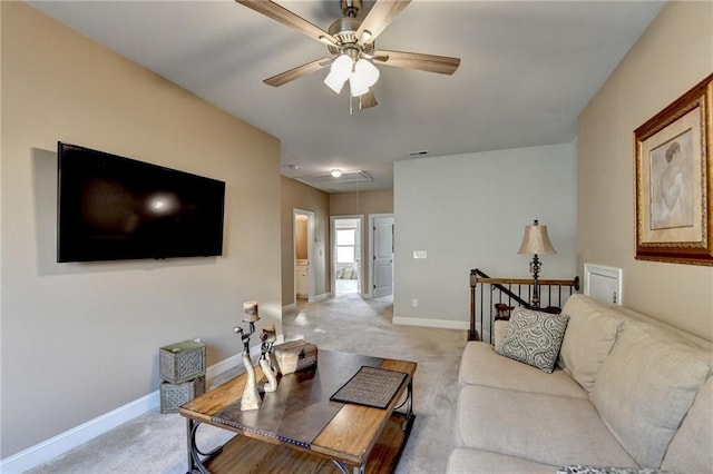 living room with baseboards, light carpet, attic access, and a ceiling fan