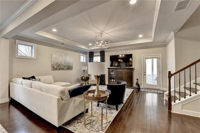 living room featuring a raised ceiling, dark wood-type flooring, and ornamental molding