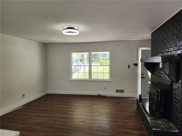 living room featuring a brick fireplace and dark wood-type flooring